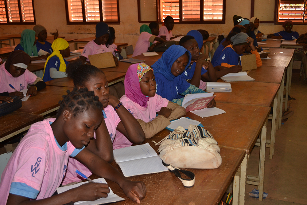 Girls writing in their notebooks at our menstrual education workshop in Nord-C school in Burkina Faso, West Africa.