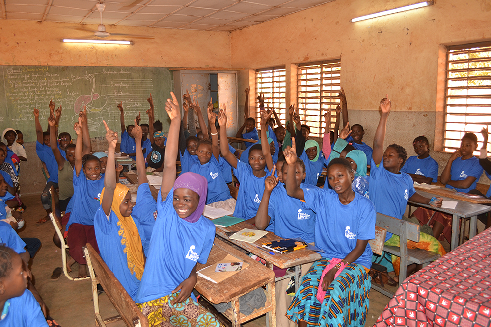 Girls raising their hands at our period education workshop in Nord-C school in Burkina Faso, West Africa.