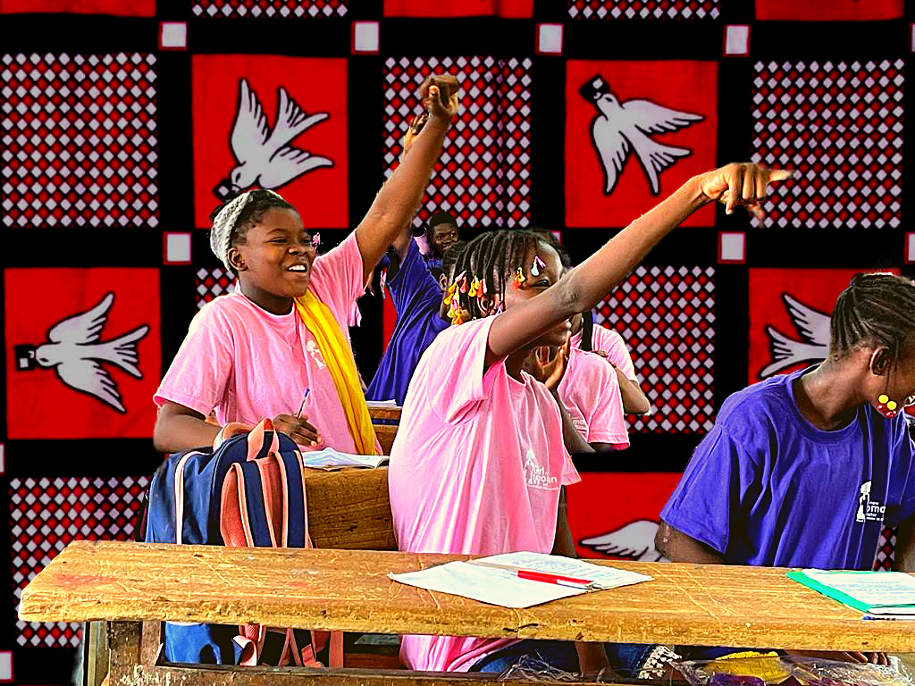 Girls raising their hands at our period education workshop in Nord-C school in Burkina Faso, West Africa. With the Luili Pende Cloth behind them.